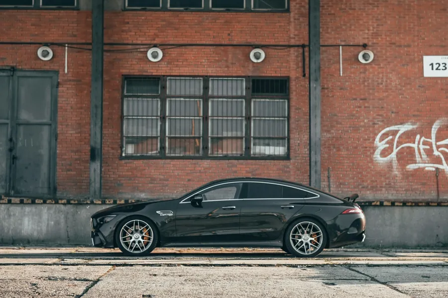 Mercedes-AMG GT 63 S negru, profil complet, în fața unei clădiri industriale