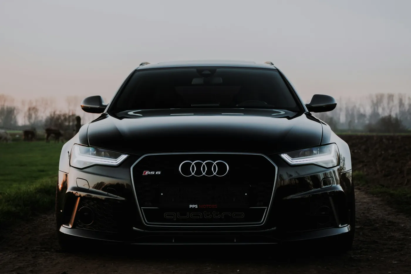 Audi RS6 Avant negru, vedere frontală joasă, la amurg, pe un drum de țară
