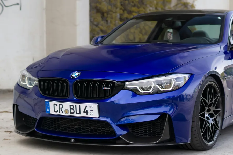 BMW M4 Competition albastru, vedere față trei sferturi, pe fundal urban