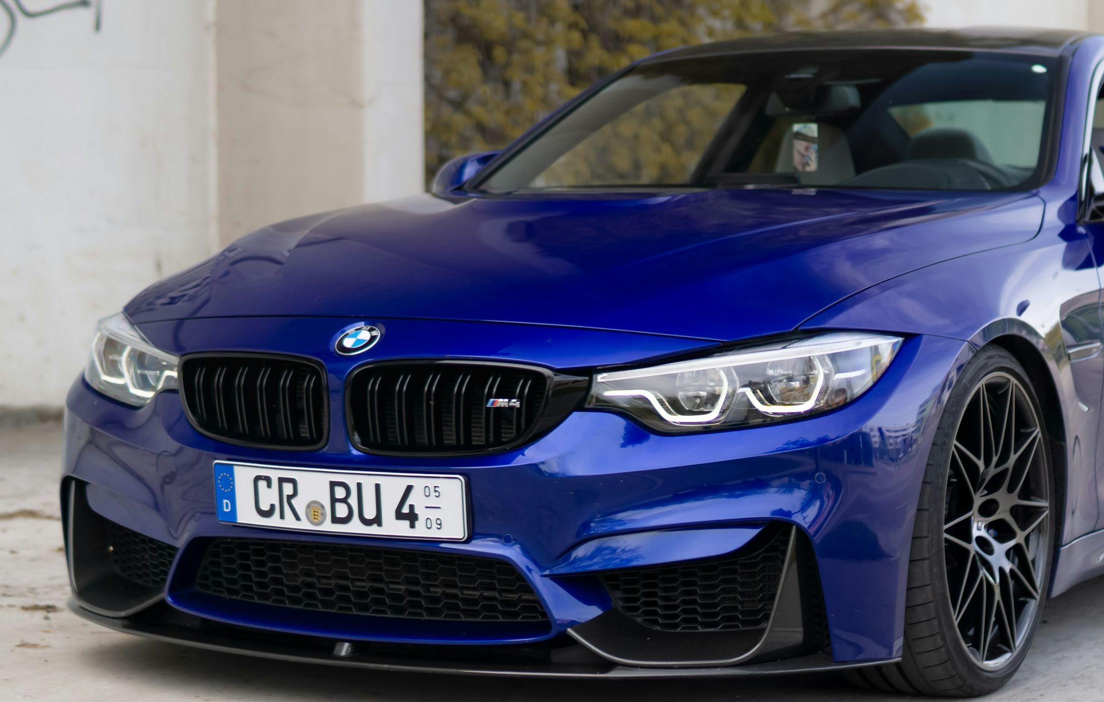 BMW M4 Competition albastru, vedere față trei sferturi, pe fundal urban