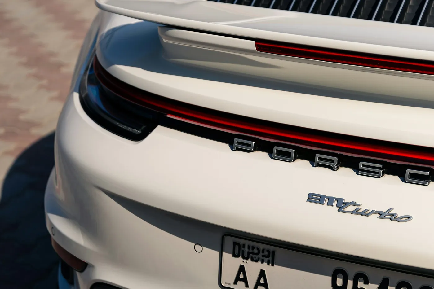 Detaliu posterior Porsche 911 Turbo alb, bandă luminoasă și inscripție Porsche