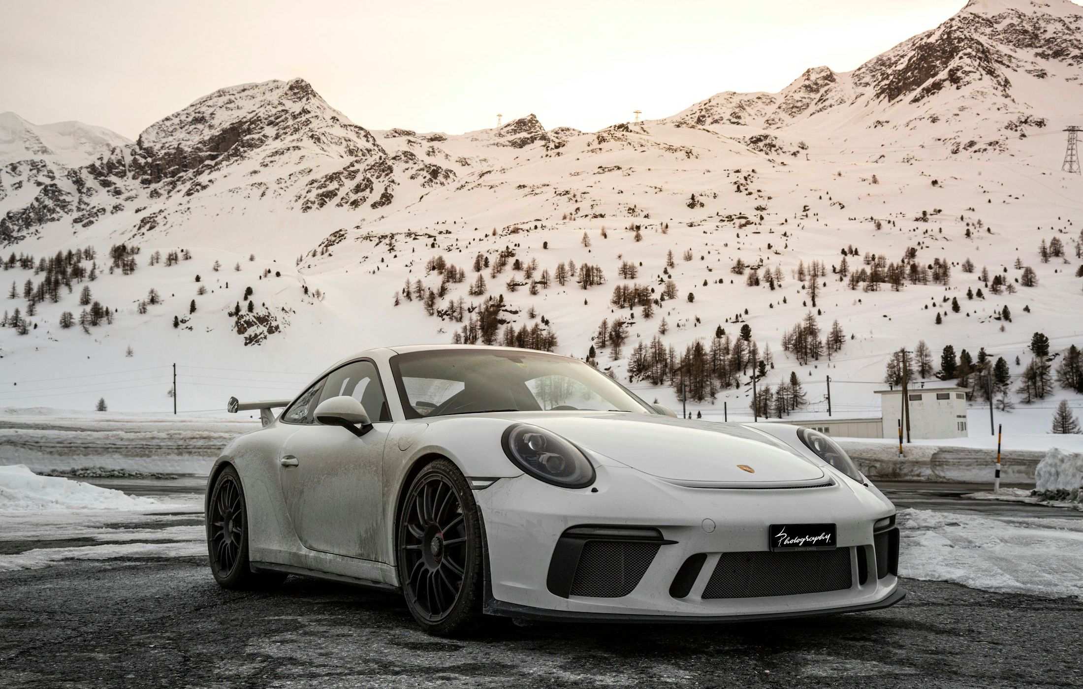 Porsche 911 Carrera alb, fotografiat pe un drum de munte, vedere față trei sferturi