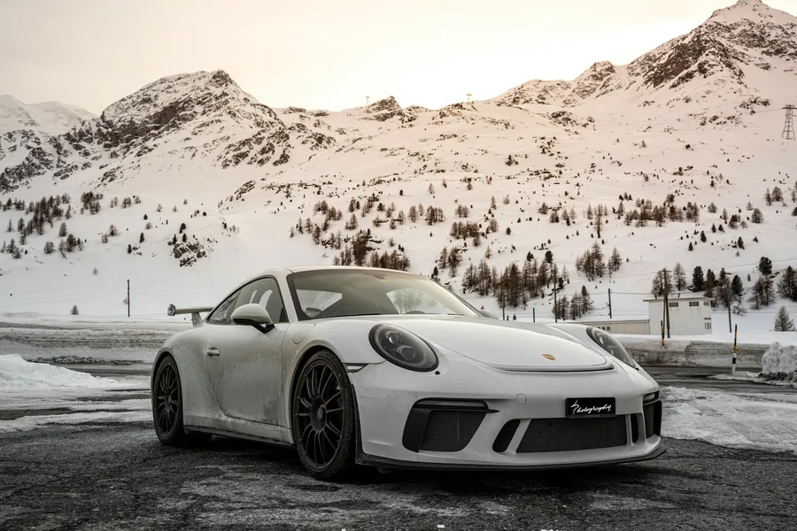 Porsche 911 Carrera alb, fotografiat pe un drum de munte, vedere față trei sferturi